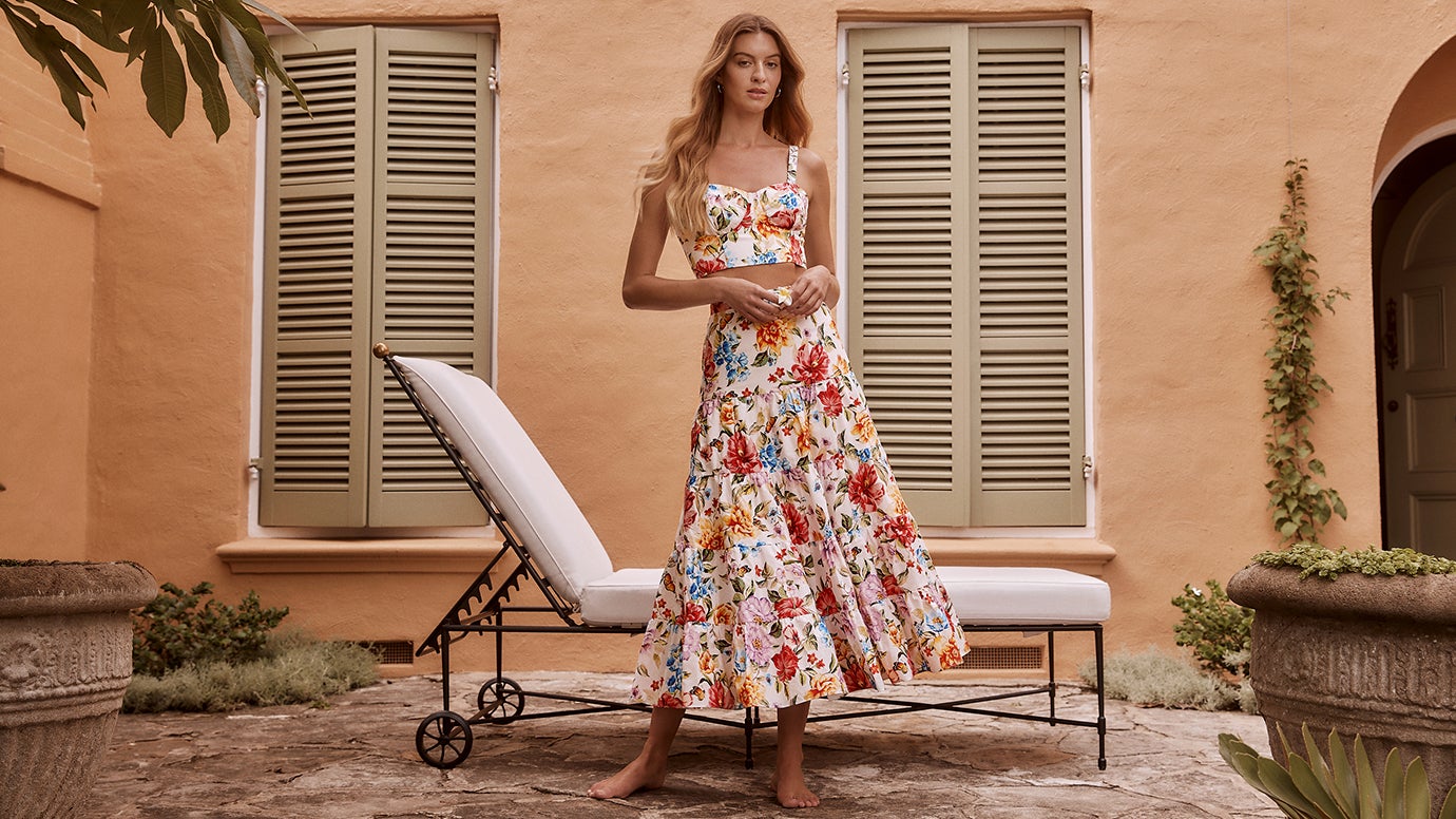 model posing in front of a large cactus in a desert landscape wearing a long, belted, white shirt dress with intricate, all-over eyelet embroidery